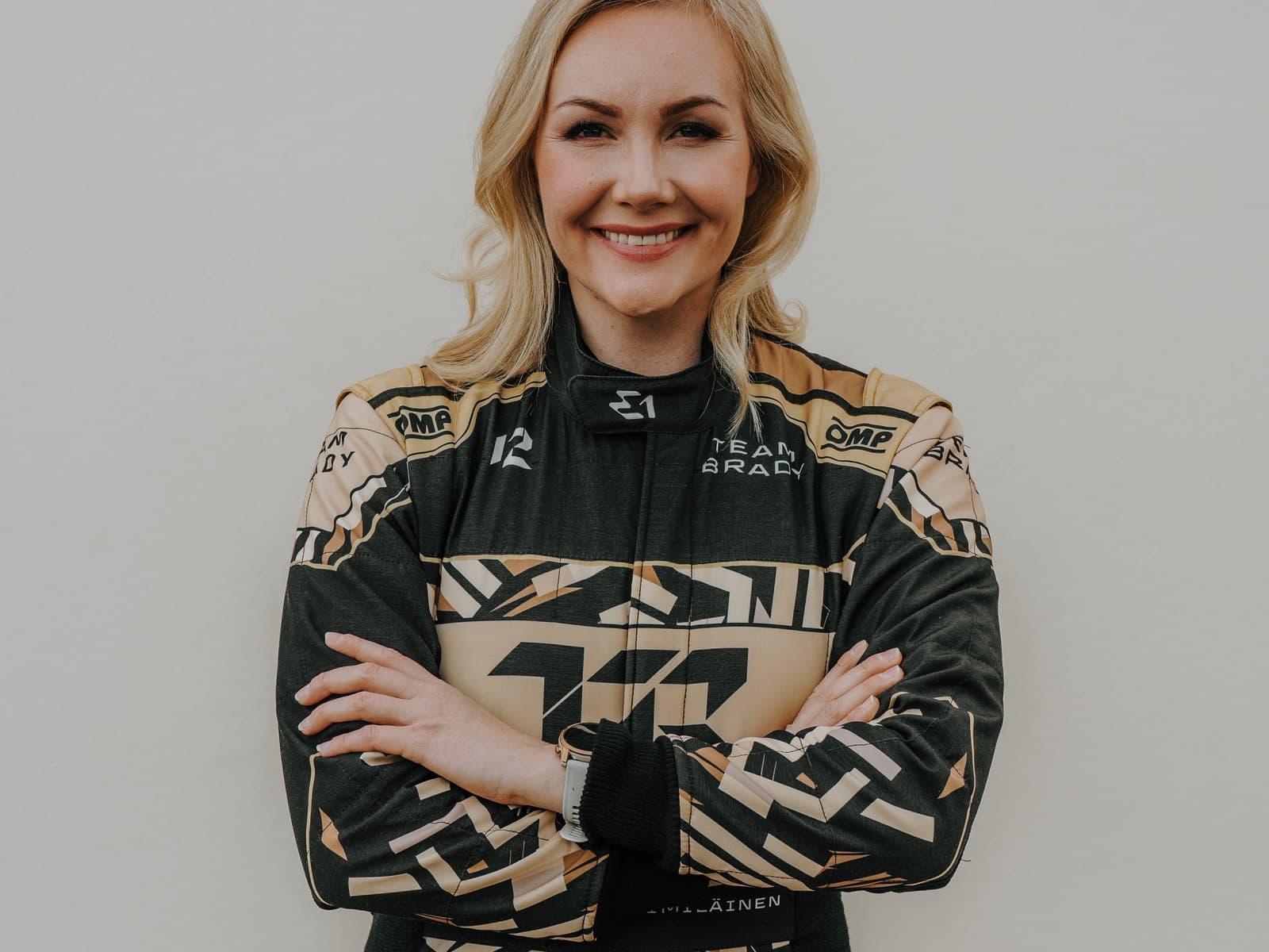 Emma Kimiläinen in Team Brady racing suit, outdoor portrait with arms crossed