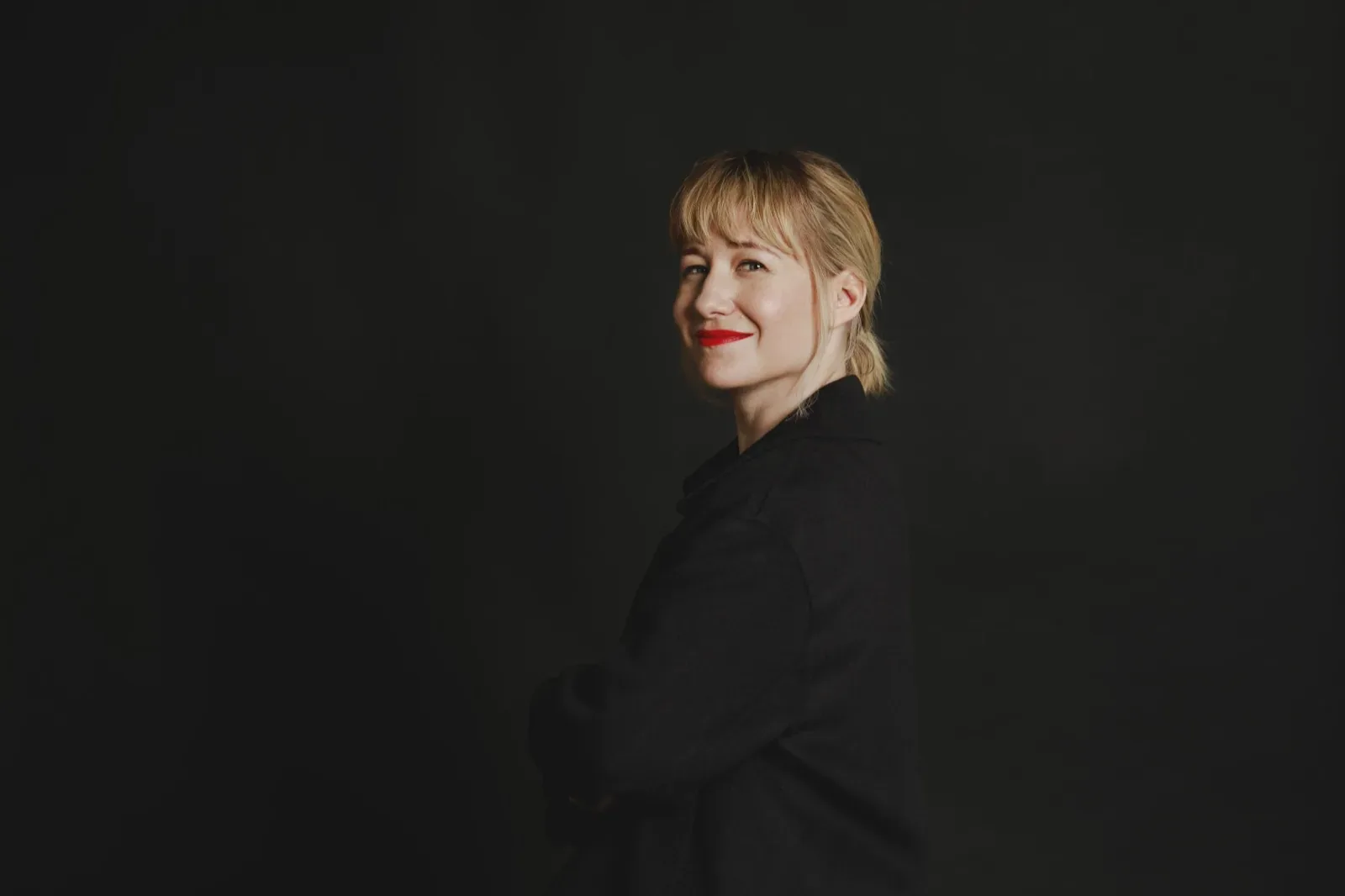 Linda Liukas in profile, black blazer against a dark studio backdrop