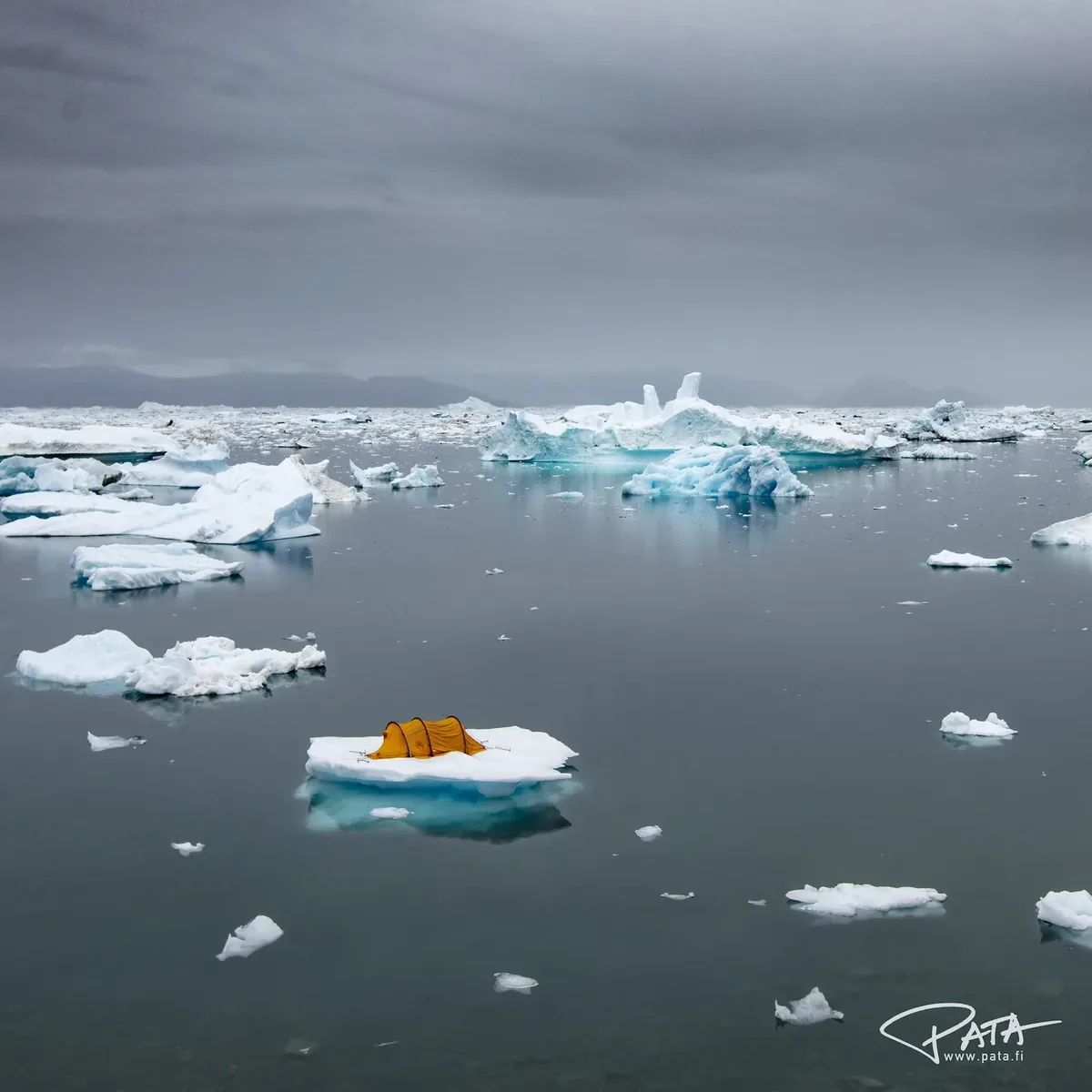 Orange expedition tent pitched on an iceberg in Arctic waters